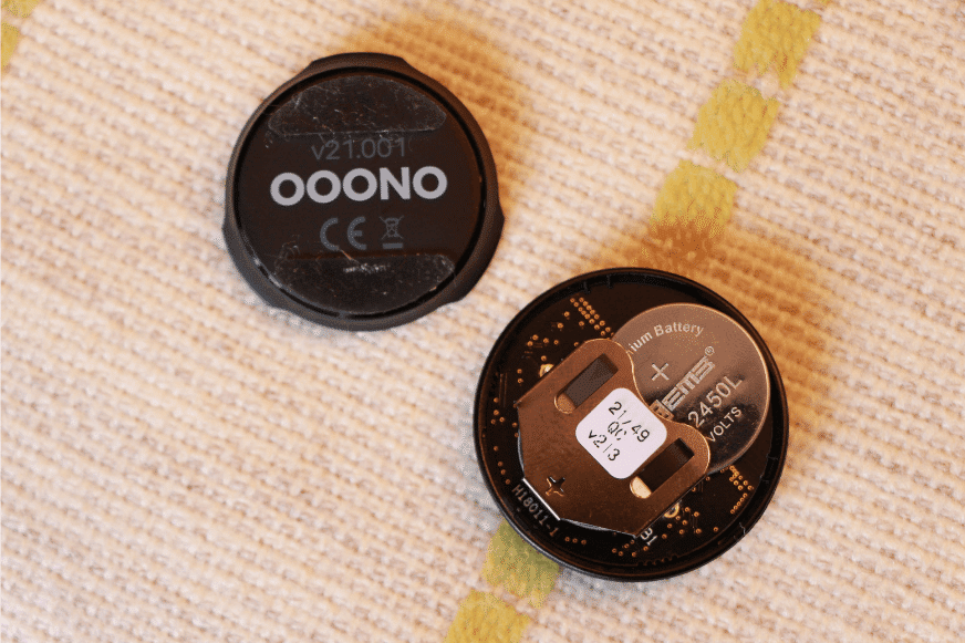 Der Ooono Co-Driver No1 Verkehrsalarm liegt offen und die CR2450 Knopfzellen-Batterie hängt in der Halterung raus